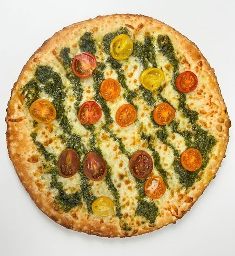 A whole pesto pizza with melted mozzarella cheese and colorful cherry tomato halves on a white background.